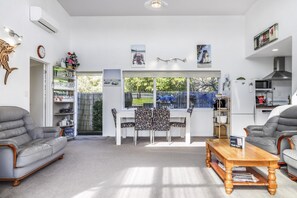 Una sala de estar moderna con comedor, cocina y un amplio ventanal con vistas al exterior.