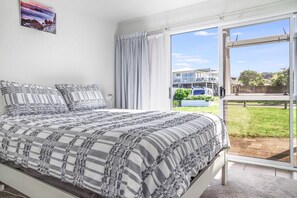 Un dormitorio con una cama grande, vistas al exterior y una ventana con cortinas.