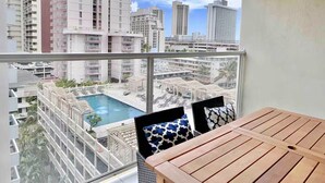 Ein Balkon mit Blick auf einen Pool und umliegende Gebäude.