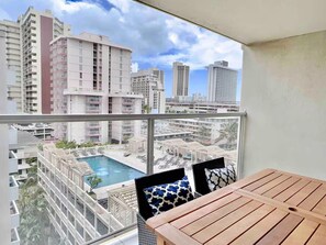 Varanda com vista para uma piscina e edifícios ao redor.