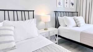 Ein Hotelzimmer mit zwei Betten, einem Nachttisch mit Lampe und Wandbildern.