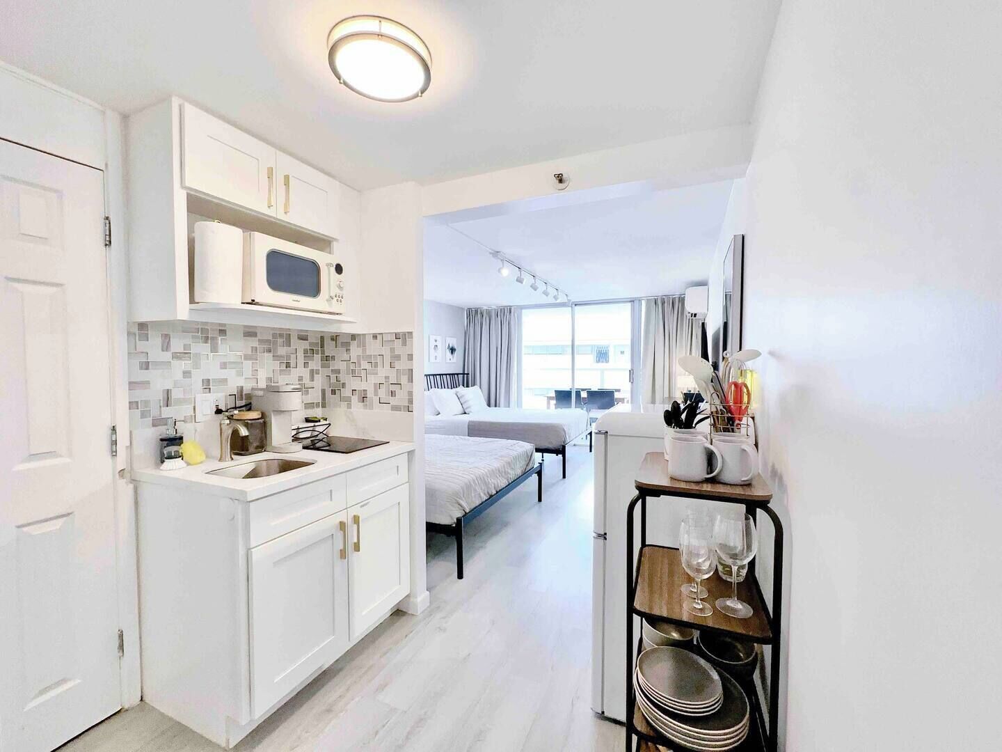Habitación de hotel compacta con kitchenette, cama, zona de comedor y vistas a la ciudad.