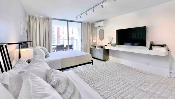 Ein Hotelzimmer mit einem Bett, einem Schreibtisch, einem Fernseher und einem Fenster mit Vorhängen.
