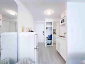 A modern kitchen with white cabinets, a built-in oven, and a countertop with various items. - Cozy Studio w/ Pool View  2 Queens & Patio Dining (Honolulu)