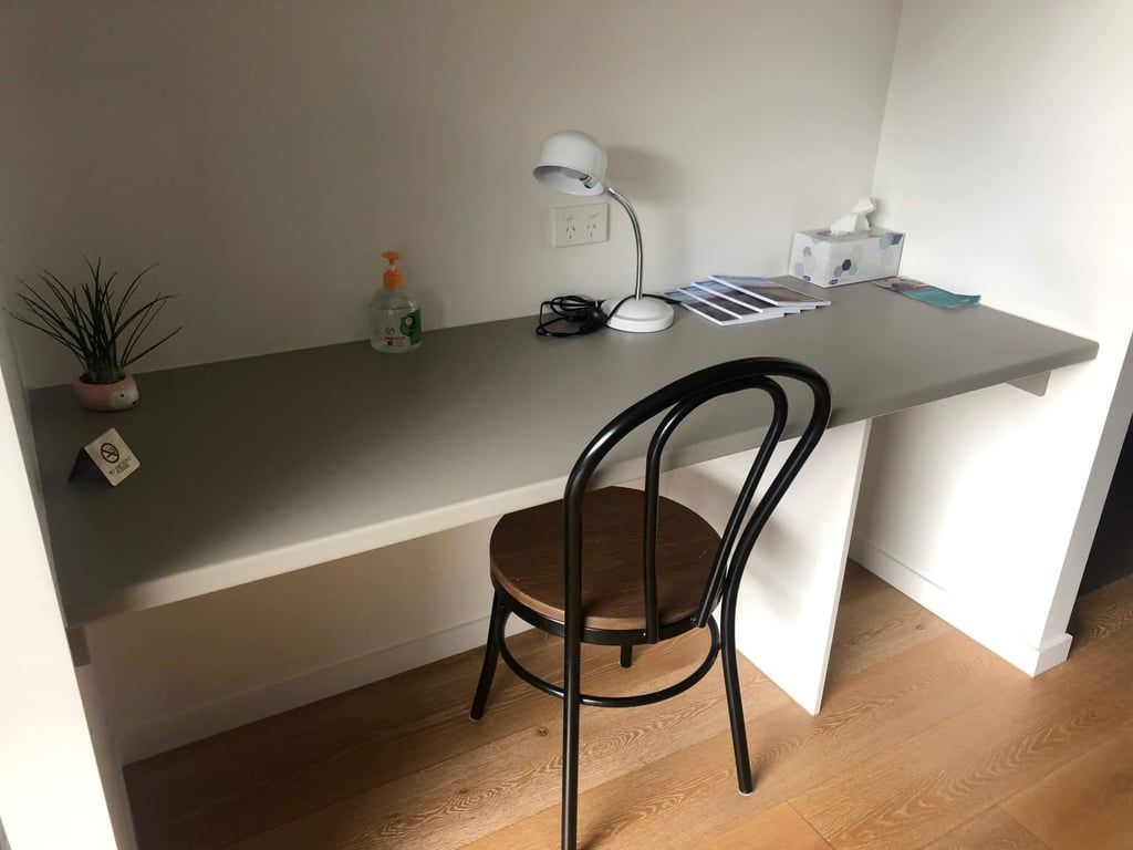 A small workspace with a desk, chair, lamp, and a potted plant.
