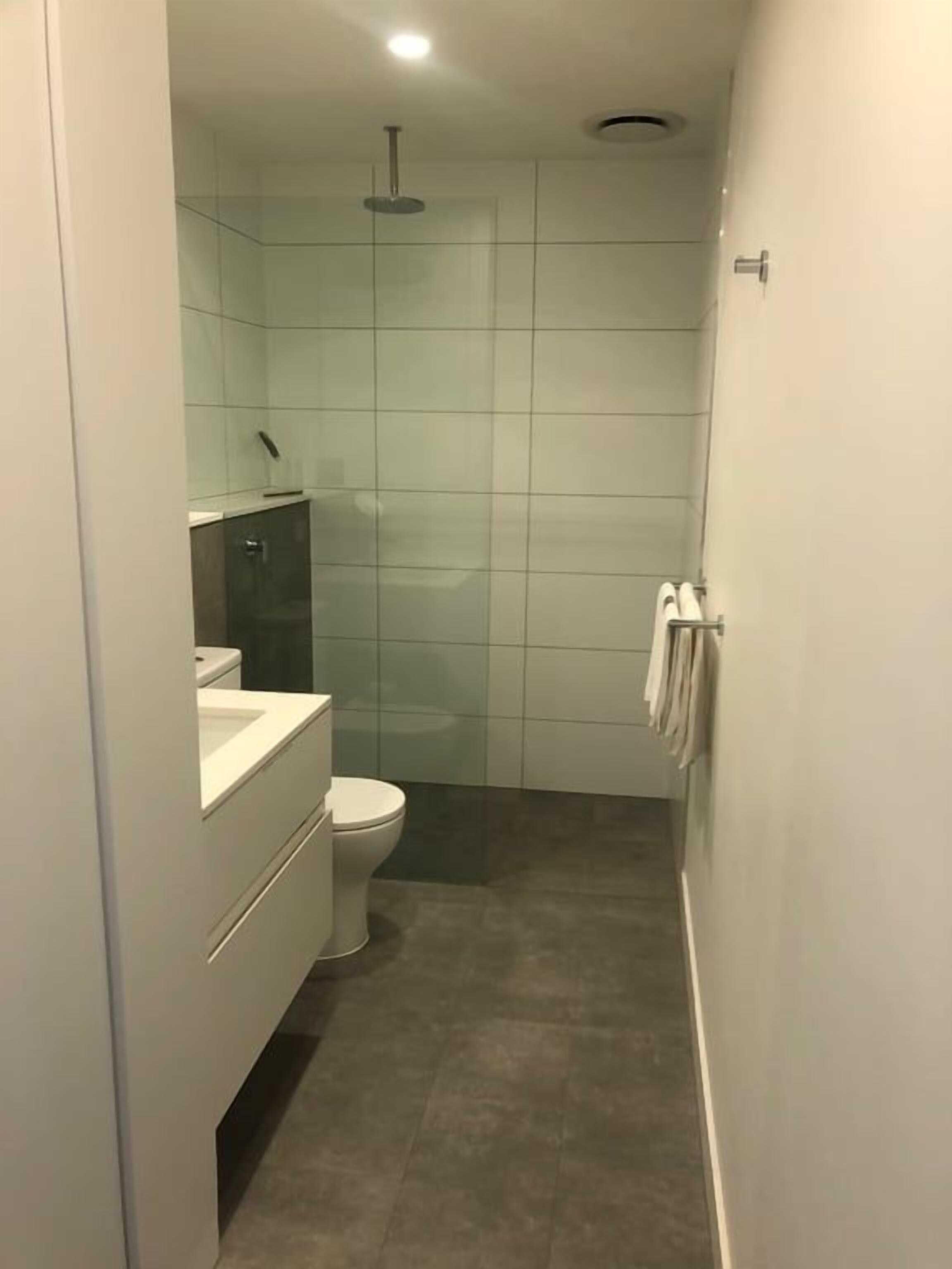A compact bathroom with a toilet, a glass shower enclosure, and a white sink.