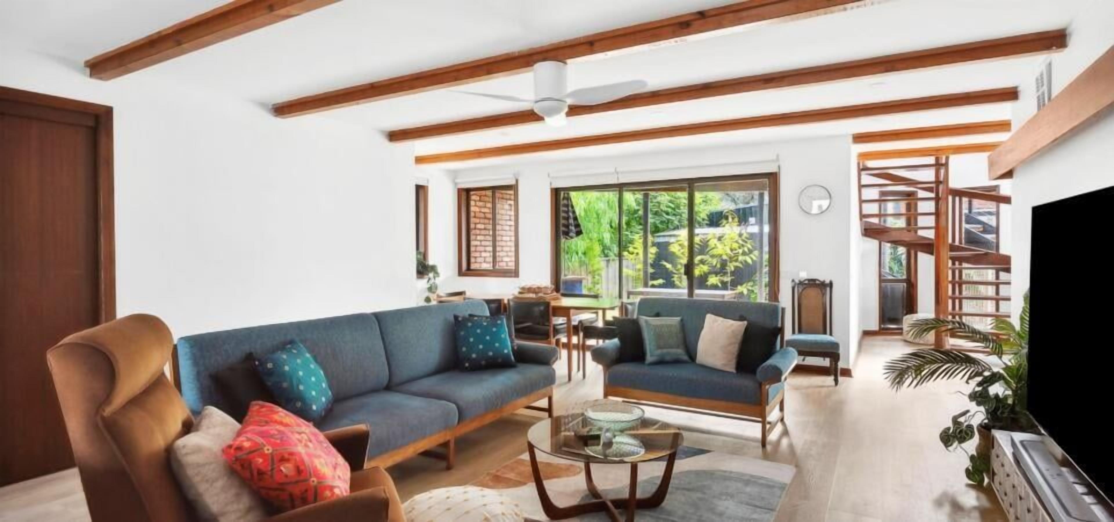 Ein Wohnzimmer mit Sofa, Sessel und Couchtisch. Am rechten Rand befindet sich ein Fernseher.