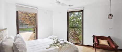 Une chambre à coucher avec un lit, une chaise et de grandes fenêtres.