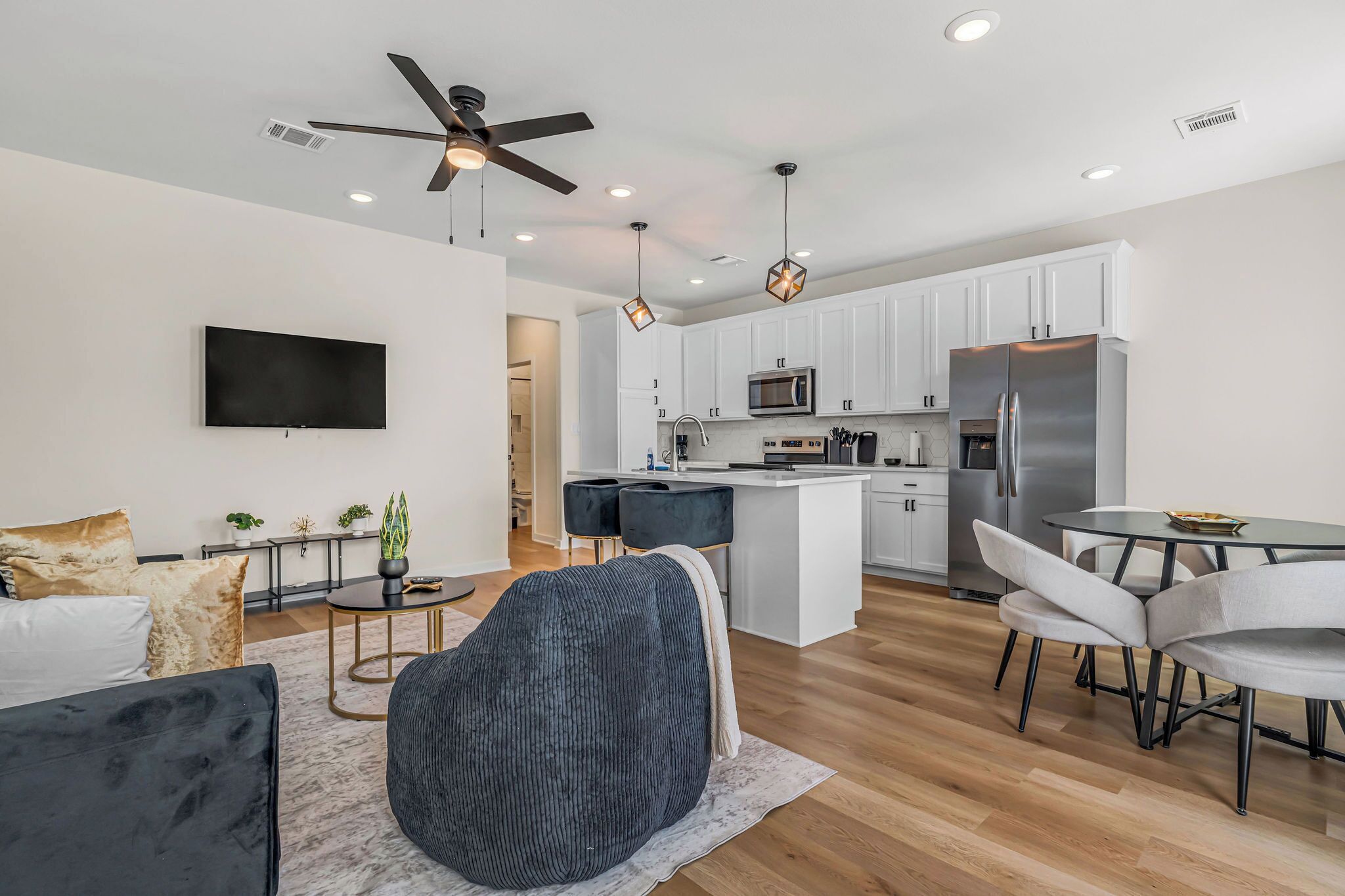 A modern kitchen with white cabinets, a built-in microwave, and a stainless steel refrigerator.