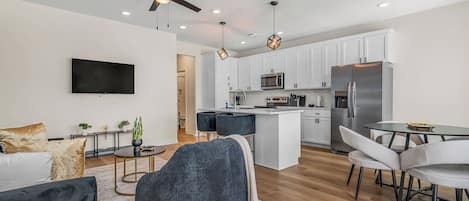 Una cocina moderna con armarios blancos, microondas integrado y un refrigerador de acero inoxidable.