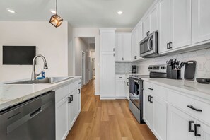 Een moderne keuken met witte kasten, roestvrijstalen apparatuur en een houten vloer.