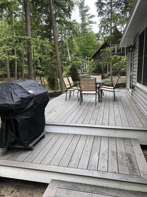 A wooden deck with a grill and outdoor furniture. - Arbor Pines - Vacation near downtown Glen Arbor (Glen Arbor)
