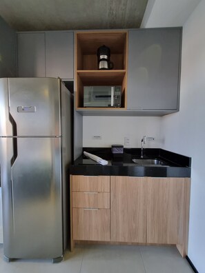 A kitchen with a stainless steel refrigerator, a microwave, and a sink with a faucet. - Studio Premium Augusta | Next Oscar Freire (São Paulo)