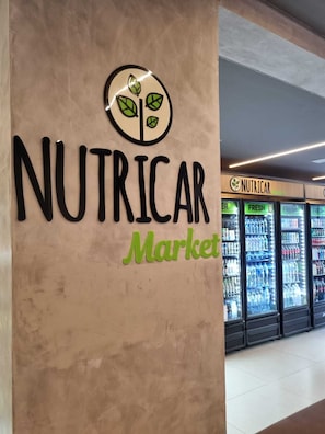 A wall with the words 'NUTRICAR Market' and a logo with leaves. - Studio Premium Augusta | Next Oscar Freire (São Paulo)