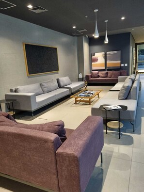 A modern living room with a sectional sofa, a coffee table, and a fireplace. - Studio Premium Augusta | Next Oscar Freire (São Paulo)
