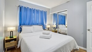 A hotel room with a large bed, two bedside tables with lamps, a mirror, and a door.