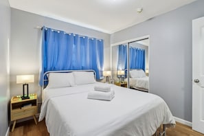 A hotel room with a large bed, two bedside tables with lamps, a mirror, and a door.