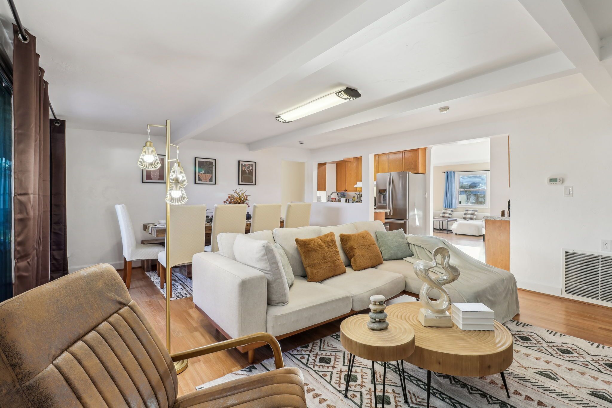 A modern living room with a sectional sofa, a wooden coffee table, and a dining area with a white table and chairs.