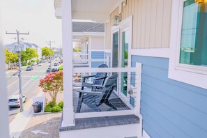 A balcony with outdoor seating and a view of a street with cars and buildings. - The Salty St. Louis (Ocean City)