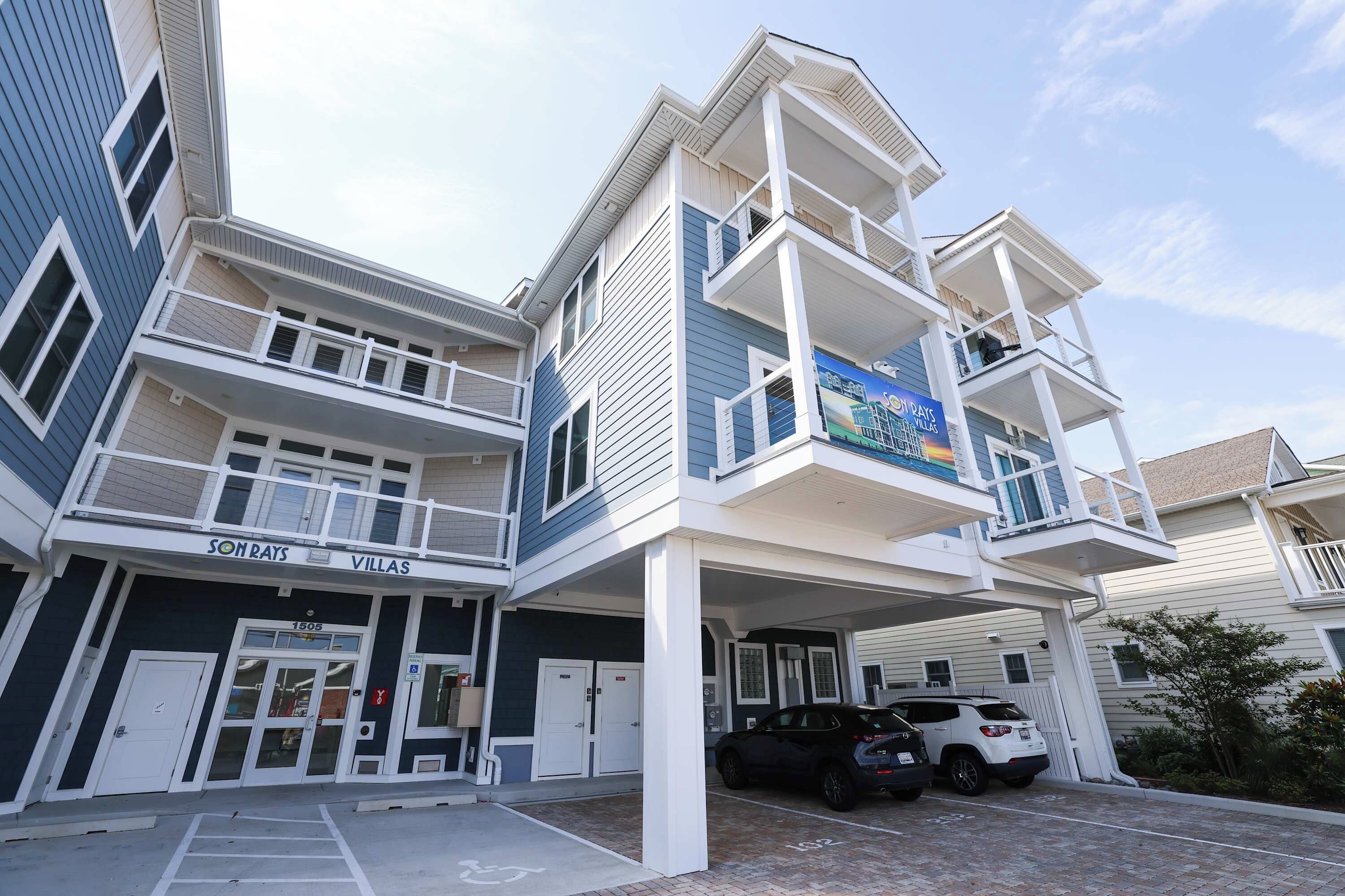 A multi-story hotel with a parking area and a sign for 'SON RAYS VILLAS'.