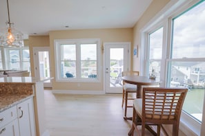 A spacious kitchen with a dining area, large windows, and a view of the neighborhood. - The Salty St. Louis (Ocean City)