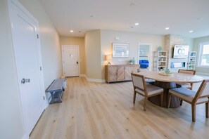 A spacious room with a wooden dining table and chairs, a bench, and a white door. - The Salty St. Louis (Ocean City)