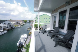 A balcony with Adirondack chairs overlooking a marina with boats docked. - The Salty St. Louis (Ocean City)