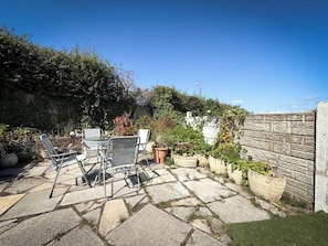 An outdoor patio with stone flooring, a metal table, and two chairs. - Cosy Southport Bungalow | 2 Bedroom with Parking (Banks)