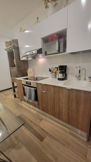 Une cuisine moderne avec des meubles en bois, un four à micro-ondes encastré, une machine à café et un évier.