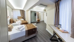 Quarto de hotel com duas camas, uma escrivaninha, uma janela com cortinas e um espelho.