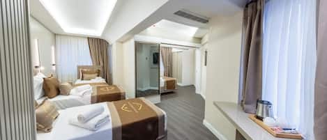 A hotel room with two beds, a desk, a window with curtains, and a mirror.