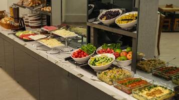 Un buffet proposant une variété d’aliments, notamment des salades, des fruits et des plats préparés.