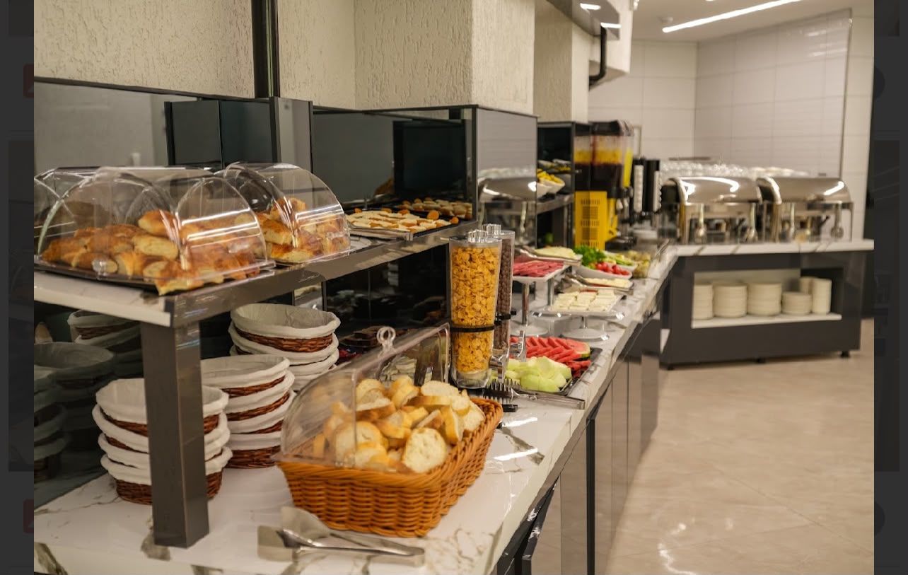 Monipuolinen buffet, jossa on tarjolla erilaisia ruokia, kuten leipää, salaatteja ja lämpimiä ruokia, ja joka on aseteltu ruostumattomasta teräksestä valmistetuille tasoille.