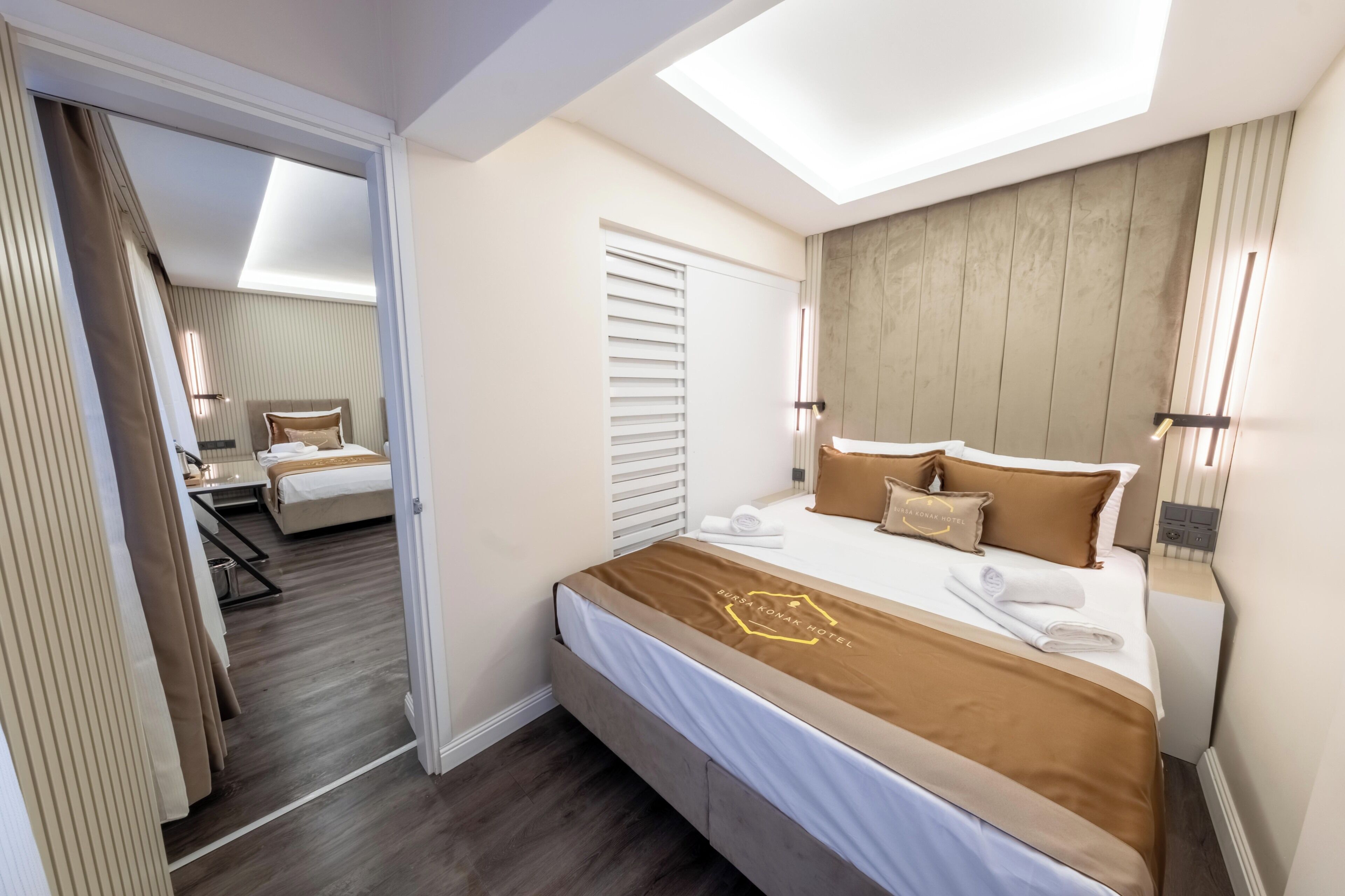 A hotel room with a bed, a desk, a chair, a window, and a door.
