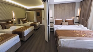 A hotel room with a large bed, two smaller beds, a wardrobe, a mirror, and a bathroom. - Bursa Konak Hotel (Bursa)