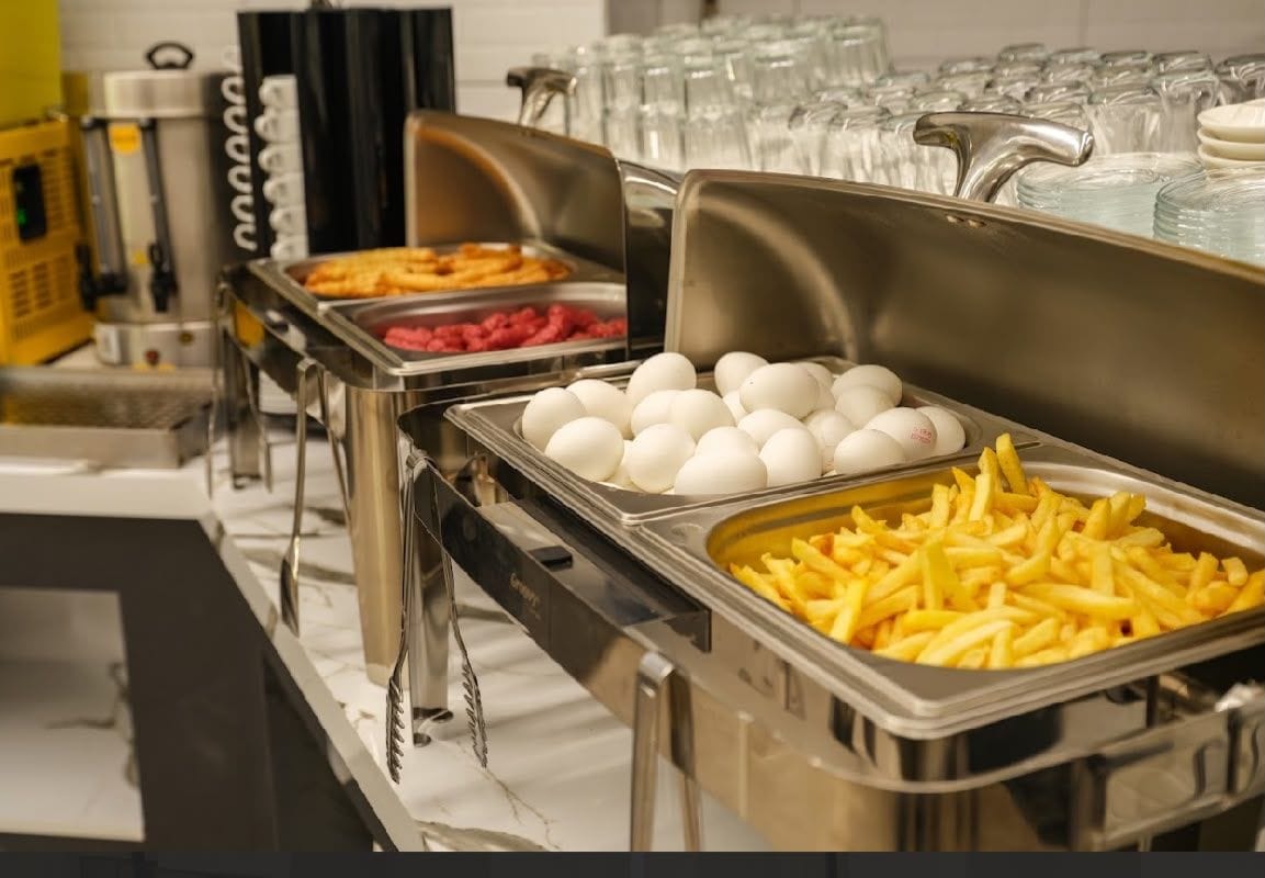 A buffet with various food options including eggs, French fries, and other dishes.