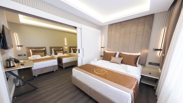 A hotel room with a large bed, a smaller bed, a desk with a kettle, and a mirror. - Bursa Konak Hotel (Bursa)