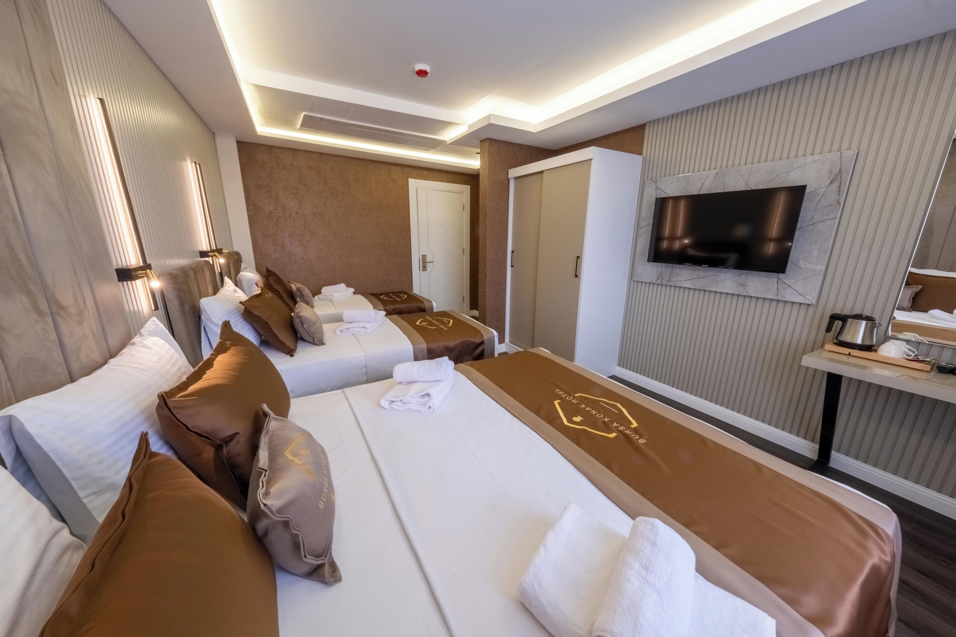 Quarto de hotel com duas camas, televisão de tela plana, frigobar e um espelho grande.
