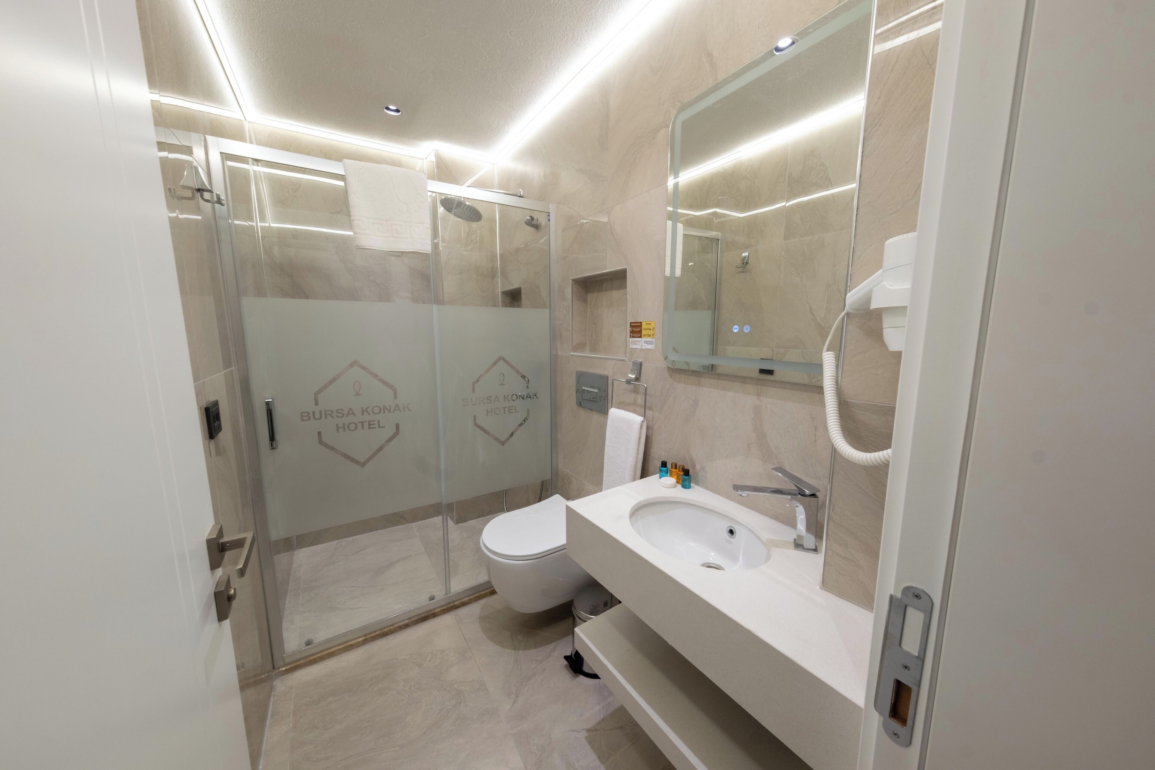 Un baño moderno con ducha envuelta en vidrio, un lavabo blanco y un espejo grande.