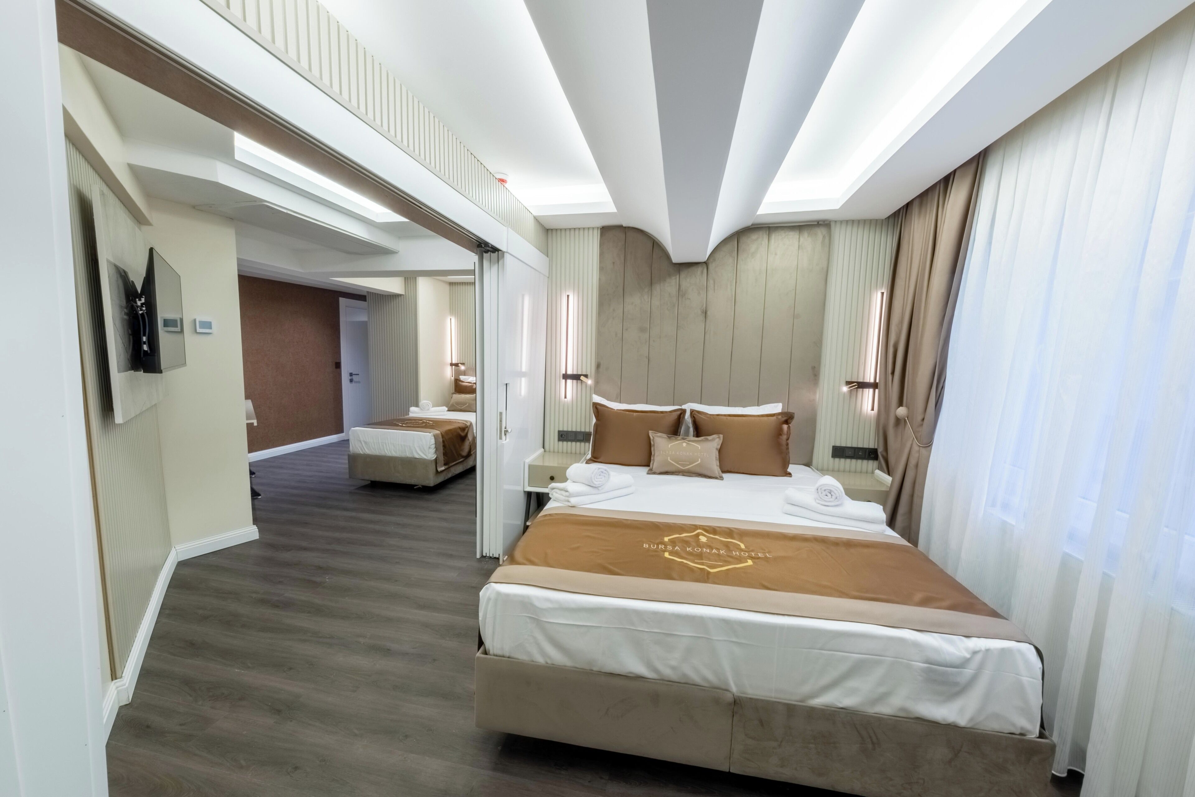 A hotel room with a large bed, a bedside table, a mirror, and a view of the hallway.