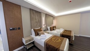 Habitación de hotel con dos camas, una mesita de noche, un escritorio y un espejo.