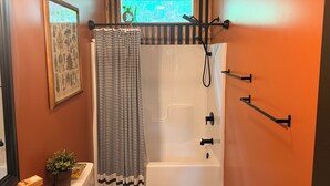 Une salle de bain avec une baignoire, une douche, un rideau à rayures et une fenêtre donnant sur un beau paysage.