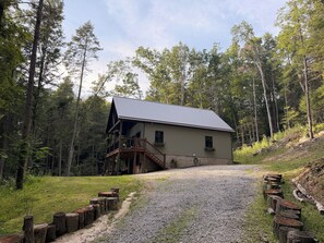 Eine Hütte mit einer Veranda, umgeben von einem Wald.