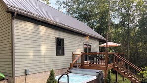 Une maison avec une terrasse, un jacuzzi et un petit arbre dans le jardin.