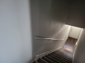 A staircase with a handrail, carpeted steps, and a white door at the bottom. - Spacious 3-bedroom apartment with AC in beautiful Austin (Austin)