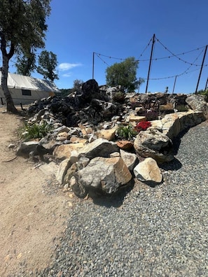 A gravel area with large rocks and a white tent-like structure in the background.