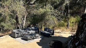 An outdoor seating area with a sofa and chairs, a rug, and a grill. - Moonshadow Flat Glamping Campground (Penn Valley)