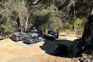 An outdoor seating area with a sofa and chairs, a rug, and a grill.