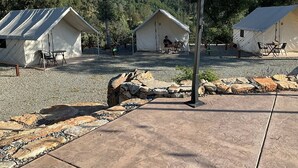 Un terrain de camping avec deux tentes, un sentier en pierre et une zone recouverte de gravier.