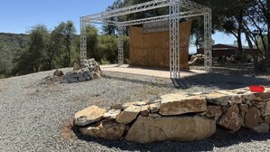 A metal structure with a wooden platform, surrounded by rocks and trees. - Moonshadow Flat Glamping: Gypsum Tent (Penn Valley)